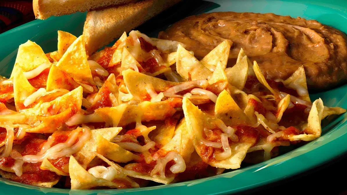 Chilaquiles Plate - Crispy tortilla chips smothered in salsa verde or roja, topped with eggs, cheese, and crema